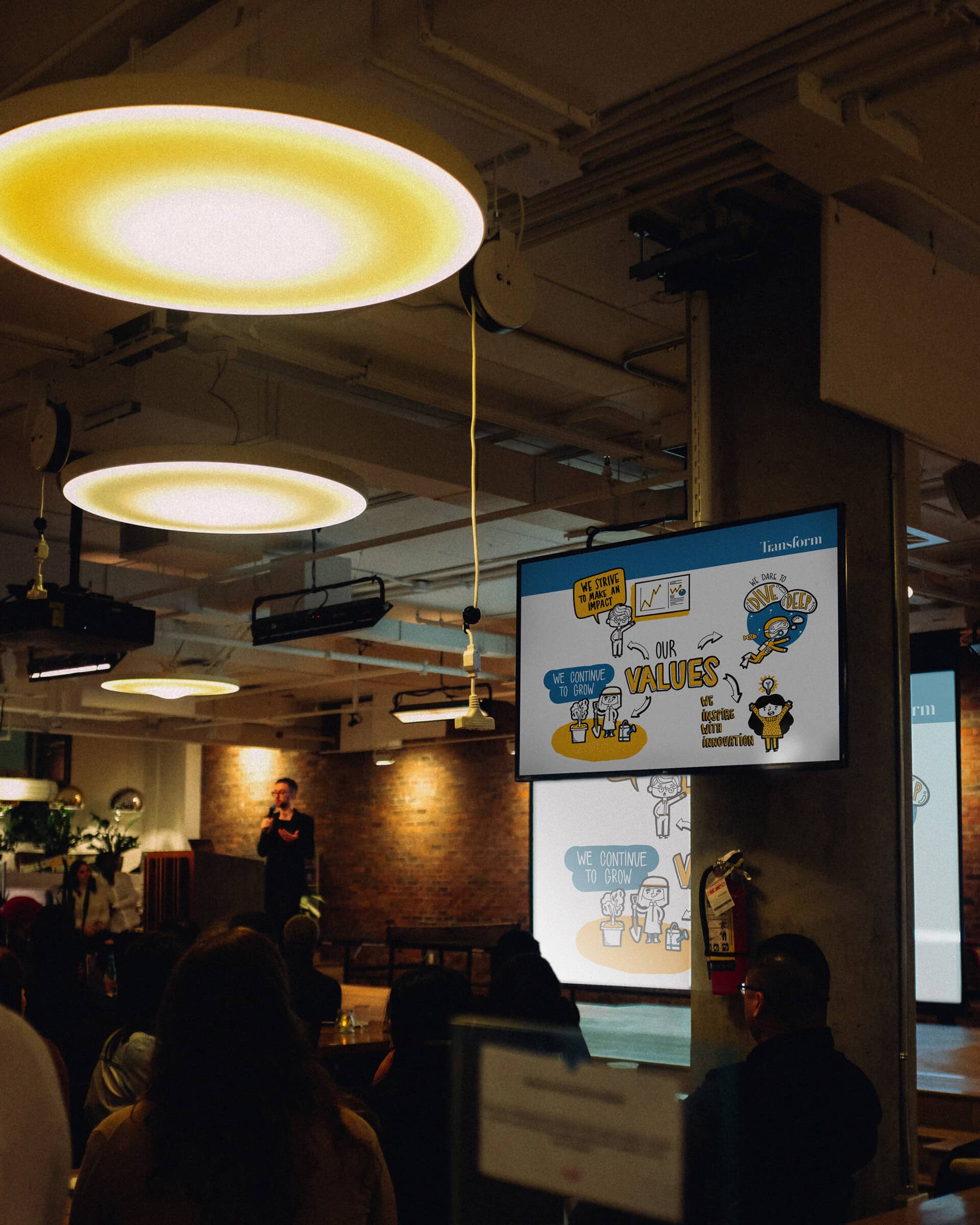 Transform's illustrated Values slide displayed on screens in a crowded room